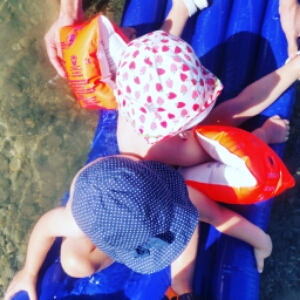 Kinder auf einee Luftmatratze im Wasser.