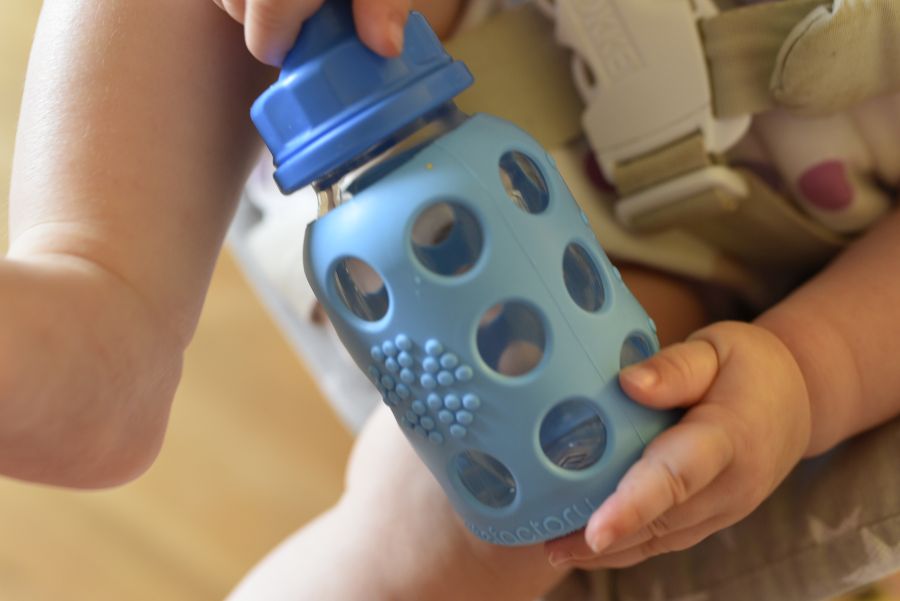 Baby hält Trinklflasche in der Hand