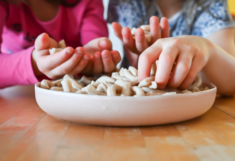 Foto von Kinderhänden mit Vollkornpasta